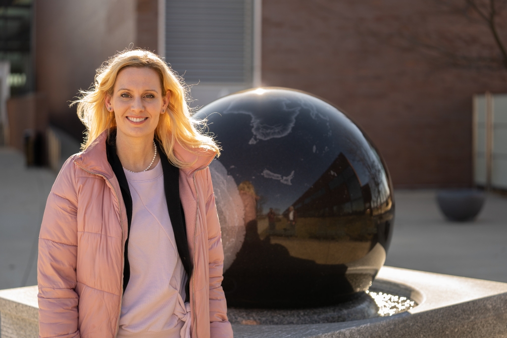 Julie Goodspeed-Chadwick posing in front of a round sculpture outside of a building