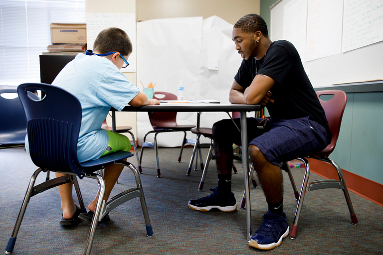 Alve'Aire Lewis helps an elementary school student at a table