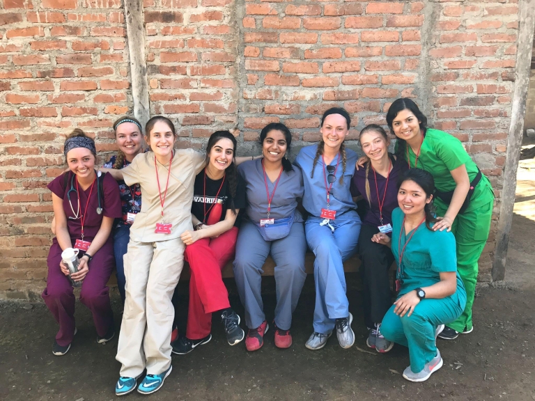 Nine students sit in front of a brick building in Nicaragua during Global Medical Brigades.