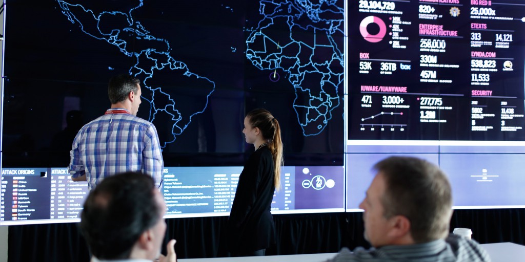 People looking at a world map on a large screen.