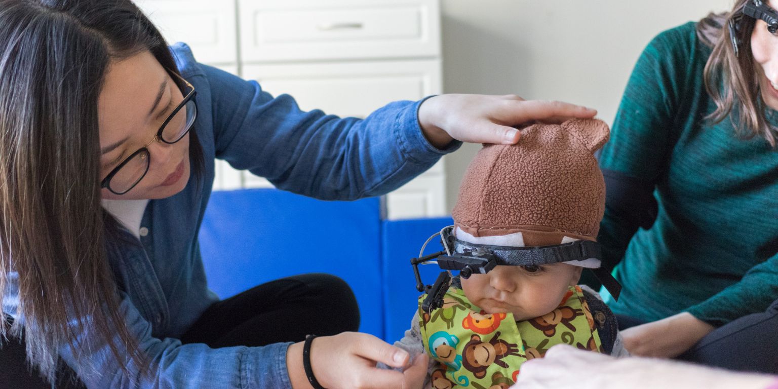 Lab researcher attaches head-mounted camera to child. 