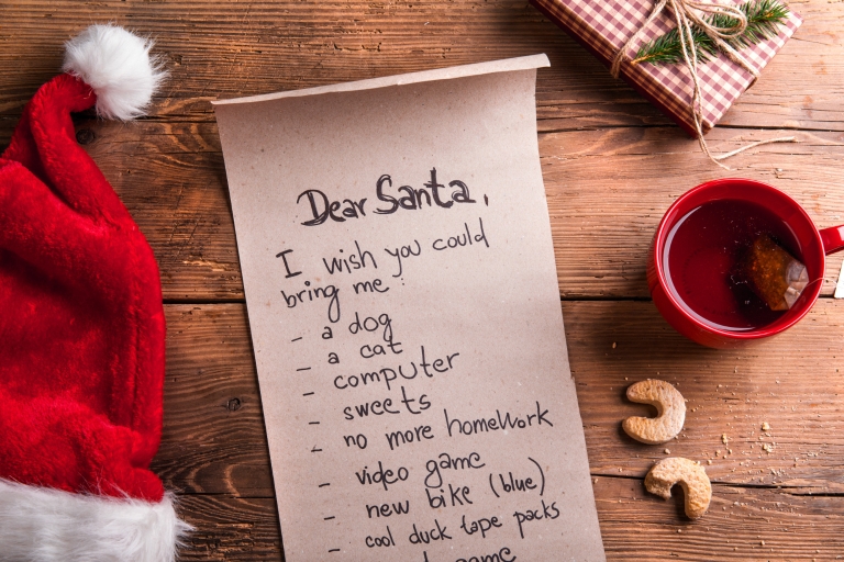 A wish list for Santa on a wooden table.