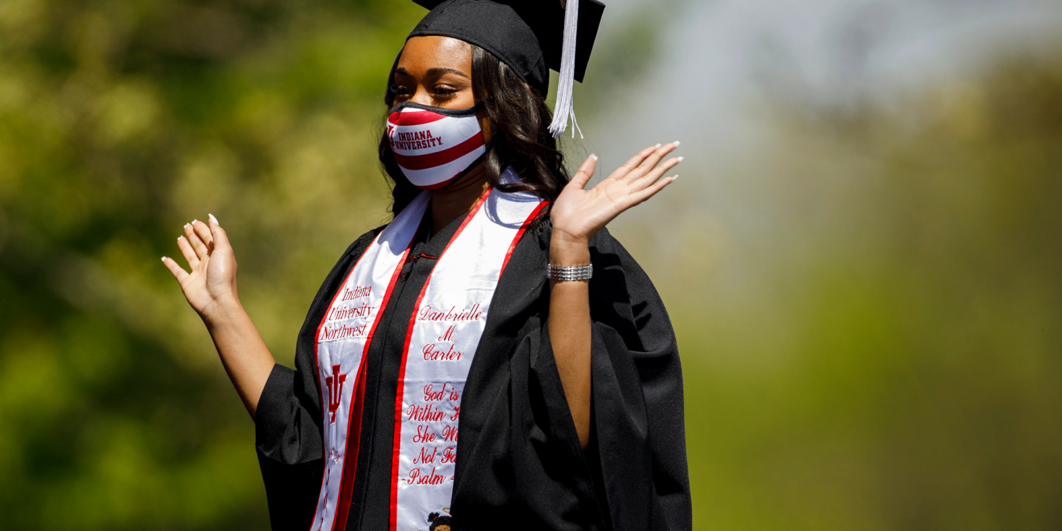 A graduate raises her hands in celebration while walking to stage