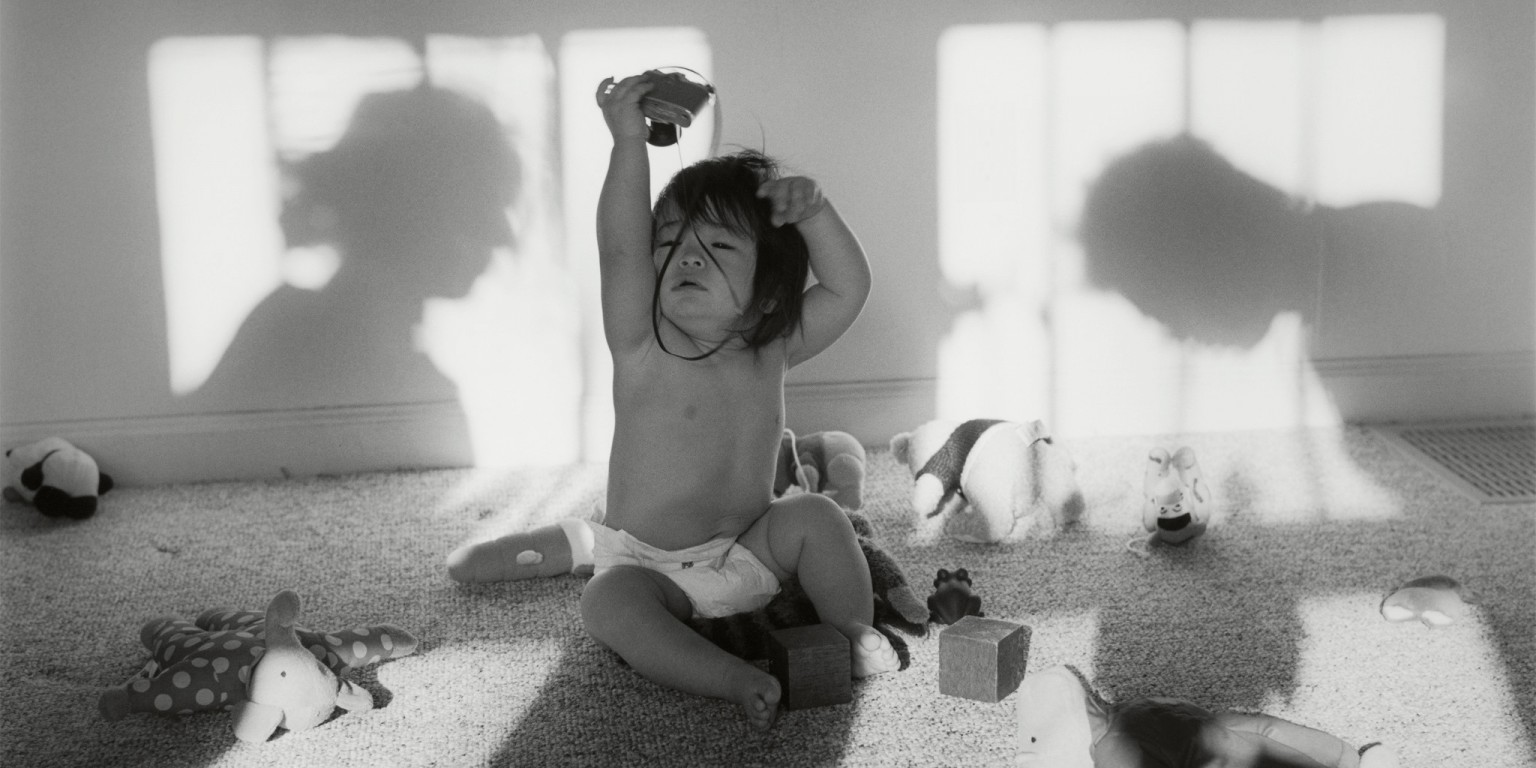 A baby holds up a toy camera