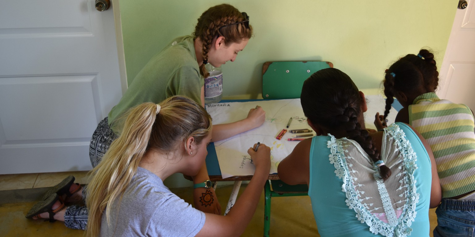 IU students Lucy Brown and Maria Bluck coloring with girls in the community La Cayota.