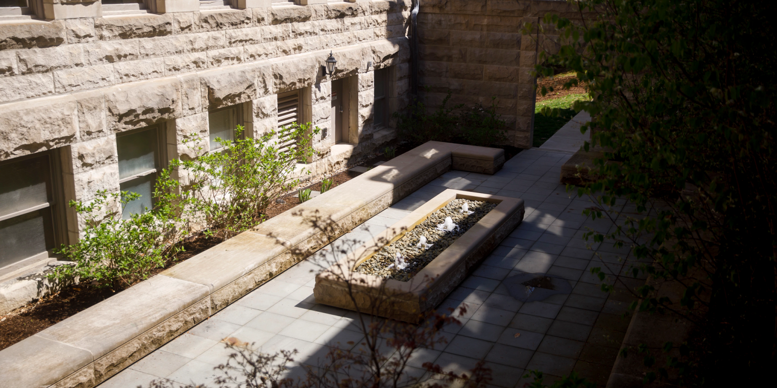 An outdoor courtyard with a fountain in the middle and limestone seating all around 