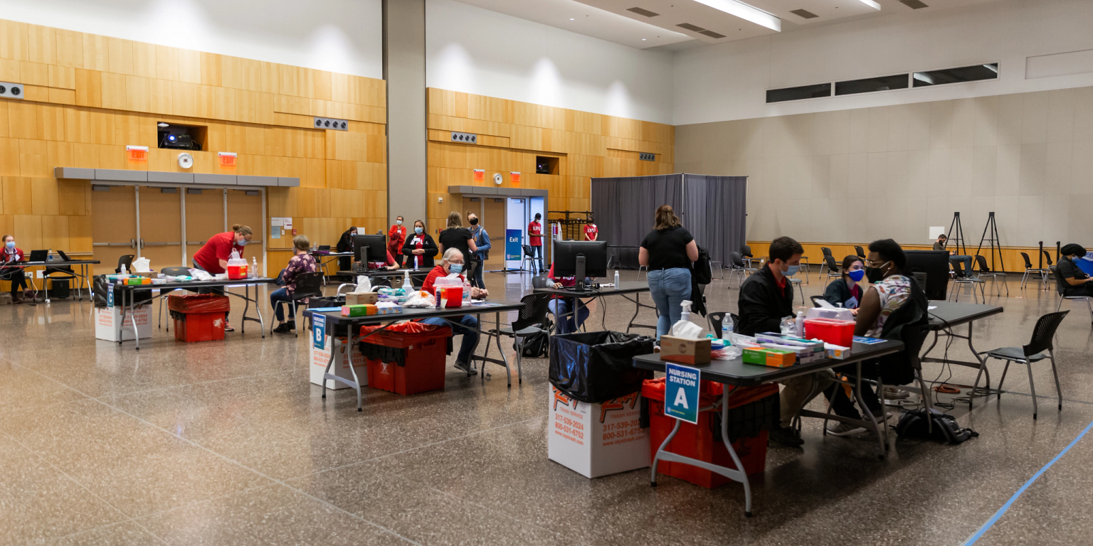 A large event room with multiple stations for vaccinations