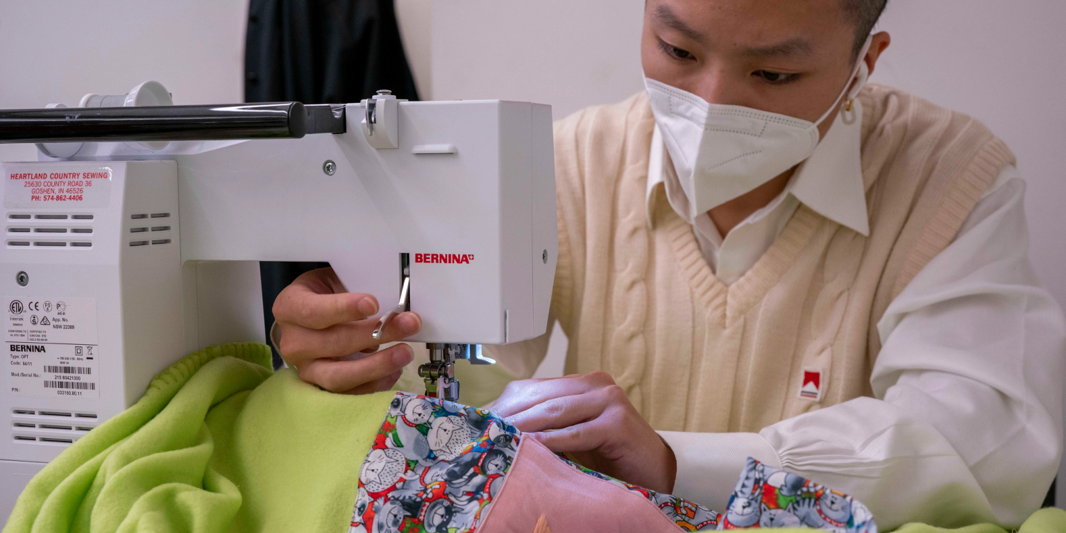 A student uses a sewing machine to make a pillow blanket