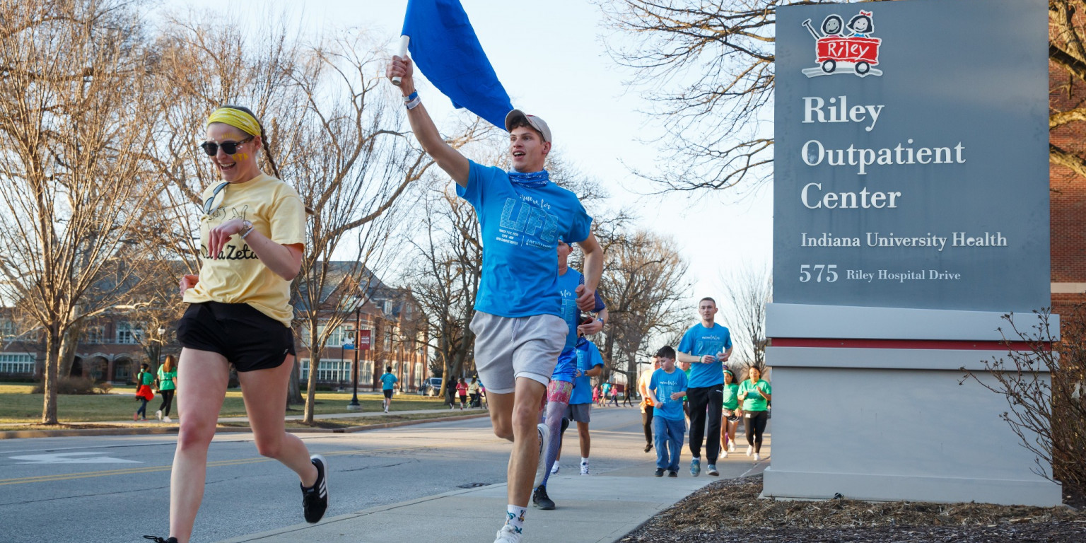 IUPUI students run down the sidewalk past the Riley Outpatient Center in team T-shirts