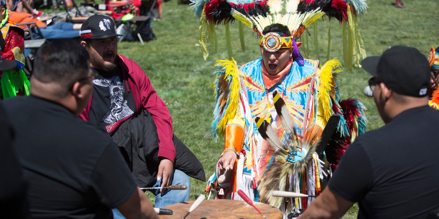Powwow participants perform in a drumming circle.