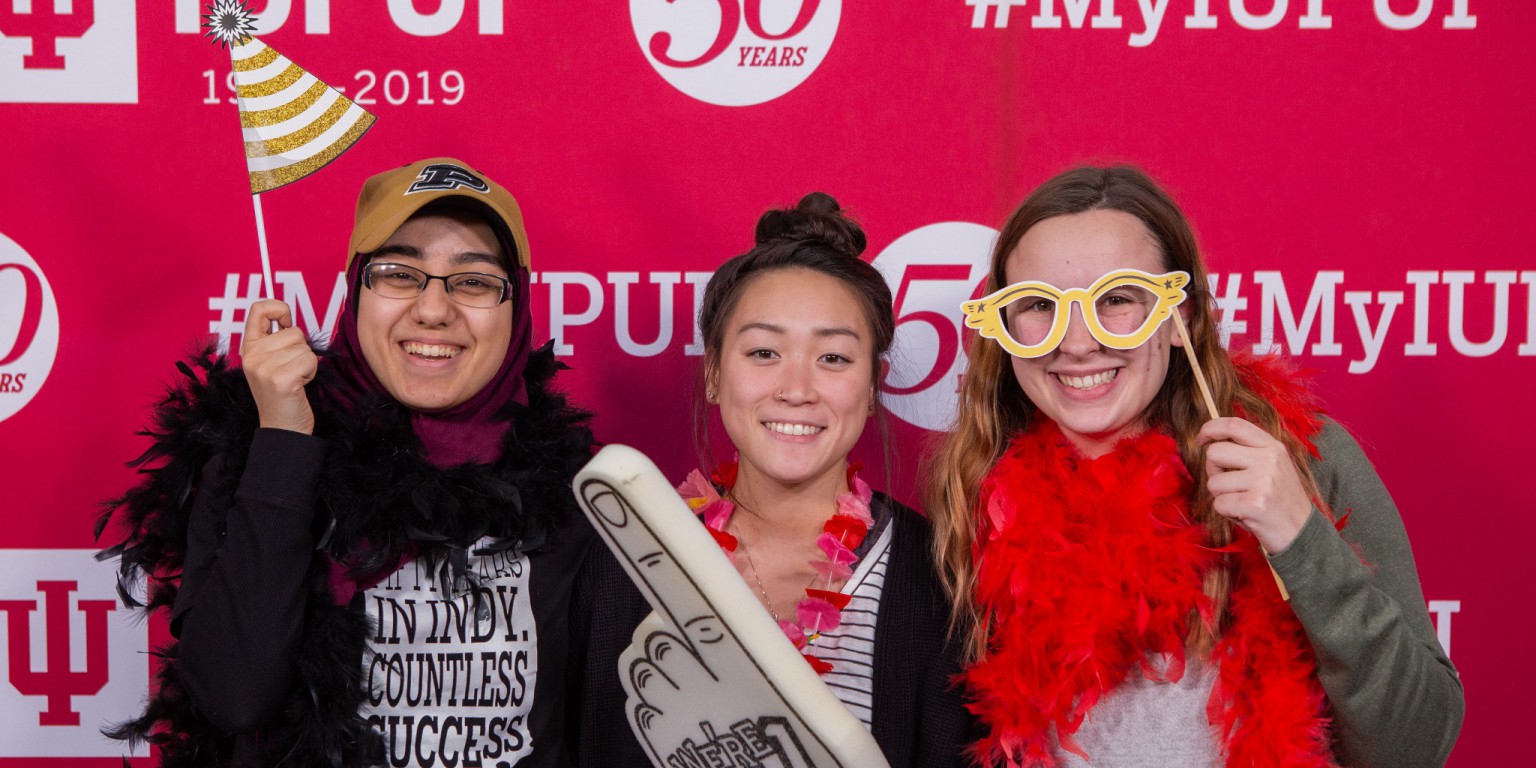 Students pose for a photo using funny props in a photo booth