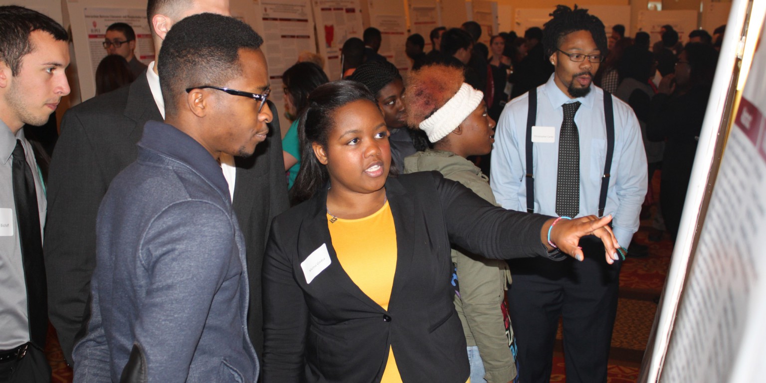 A woman explains her poster at IUPUI Student Research Day