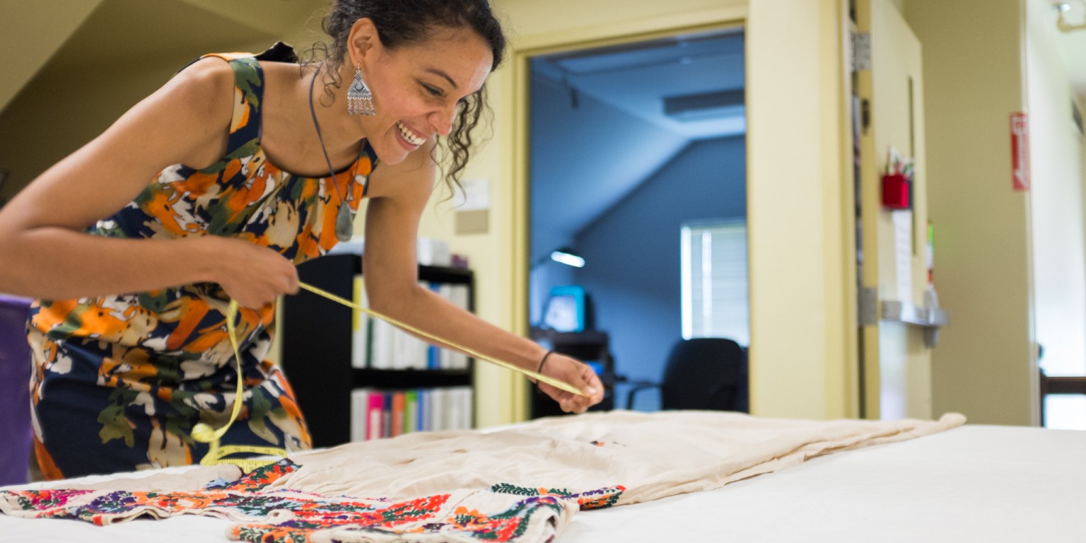 Kaila Austin measures a dress in order to custom build a mannequin to display the garment.