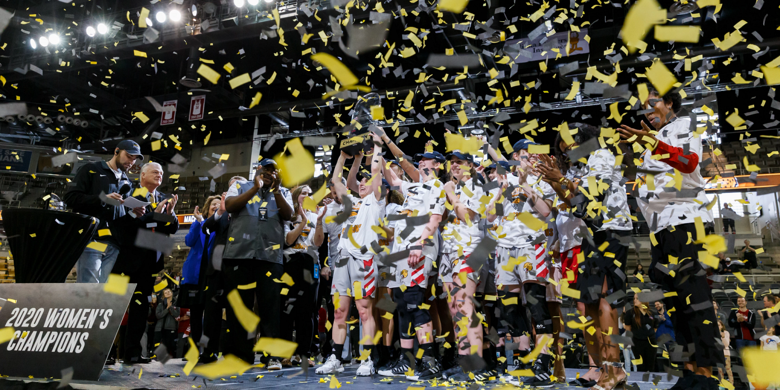 women's basketball team stands on podium with confetti falling