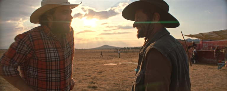 Two men in cowboy hats stand outside with the sun behind them in a scene from 'Our Time'