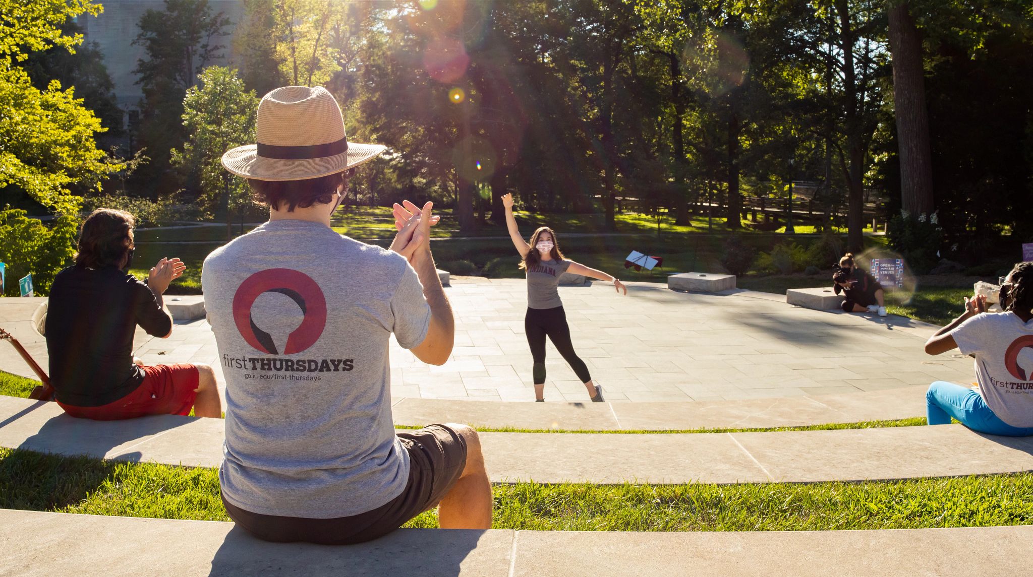 A man claps while a woman dances outdoors on IU Bloomington's campus