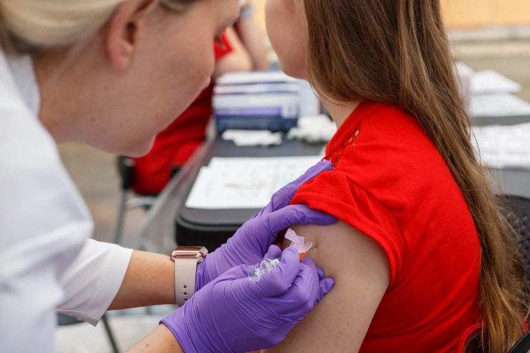 a student receives a shot in her arm from a nurse
