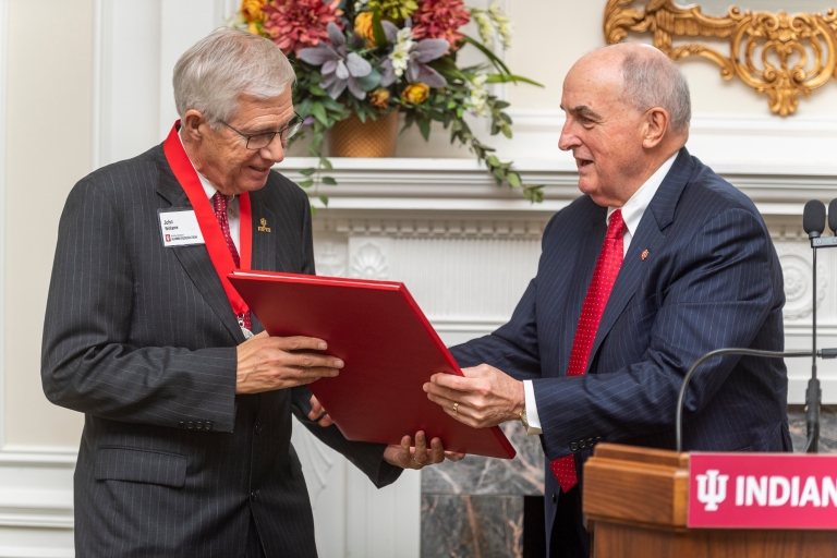 John Williams looks at the President's Medal certificate presented by President McRobbie