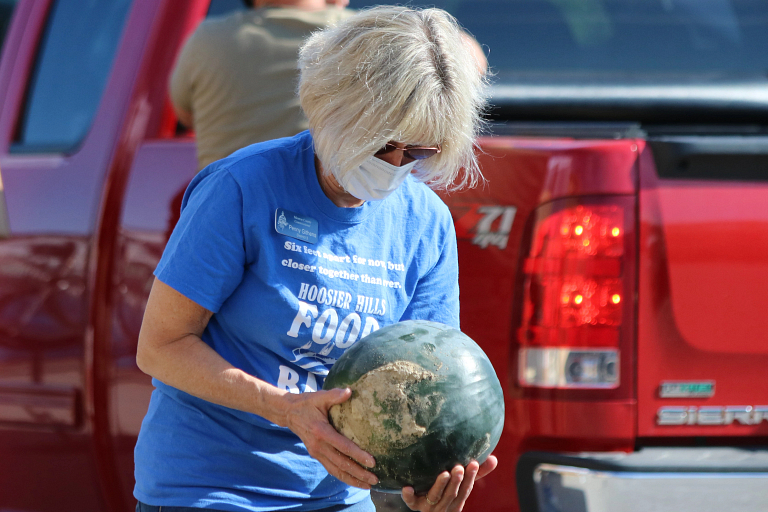 A woman carries a watermelon for a food bank giveaway