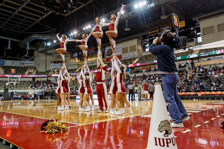 Cheerleaders lift other cheerleaders into the air during a basketball game
