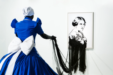 Woman in blue and white holding fabric with picture of Madam C.J. Walker