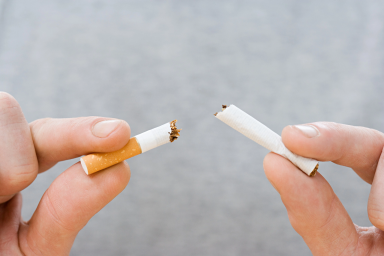 Closeup of two hands breaking a cigarette in half