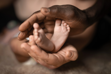 A parent holding the feet of an infant
