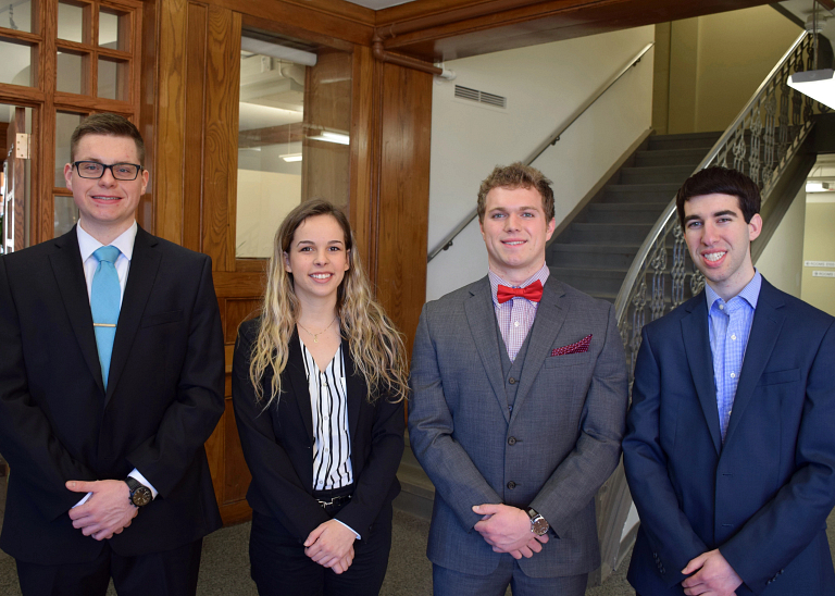 Four students in business attire pose for a picture