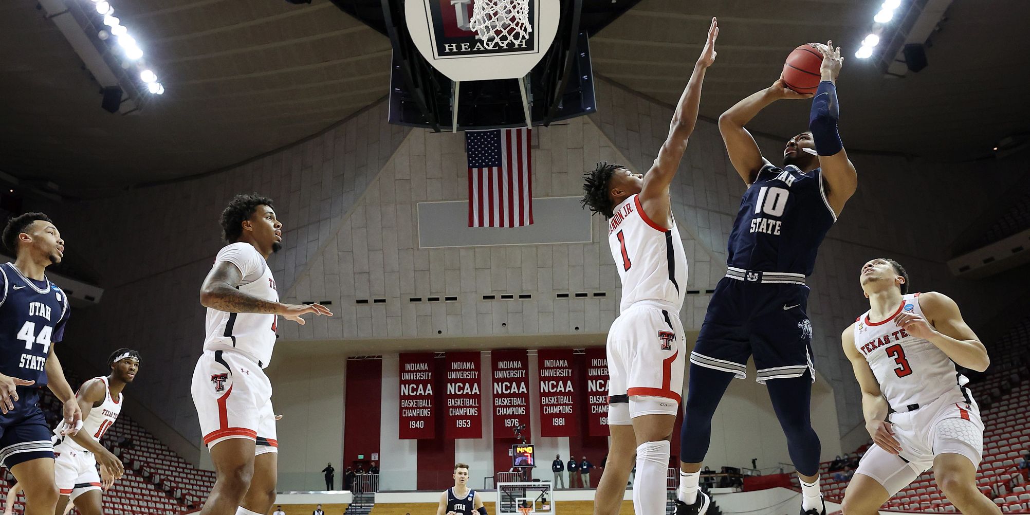 A Utah State player takes a shot over a Texas Tech defender