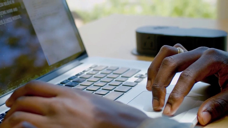 The hands of a person working on a laptop computer