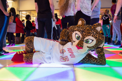 IUPUI mascot Jazzy lies on a multicolored lighted dance floor