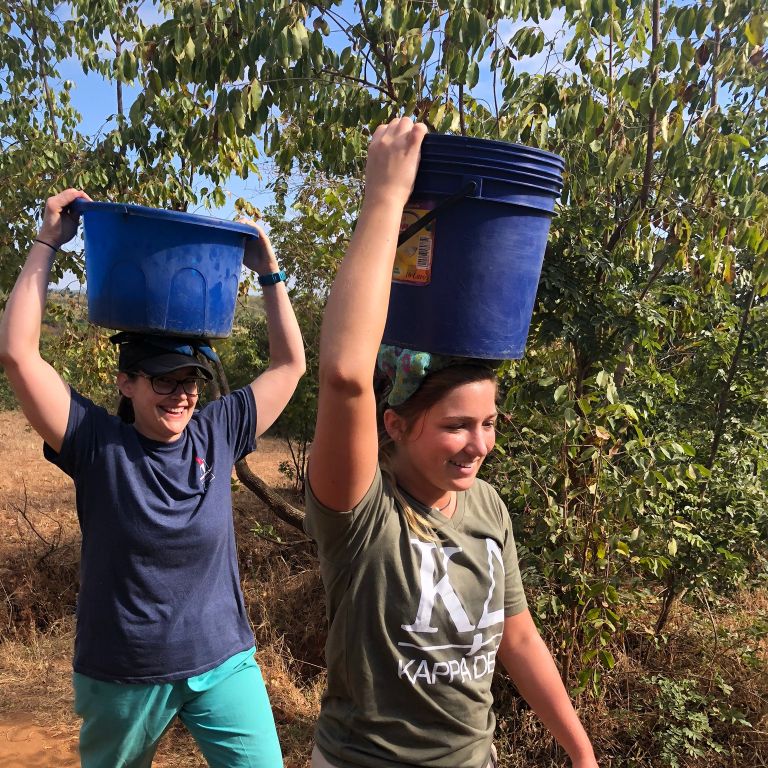 Two women carry buckets on their heads