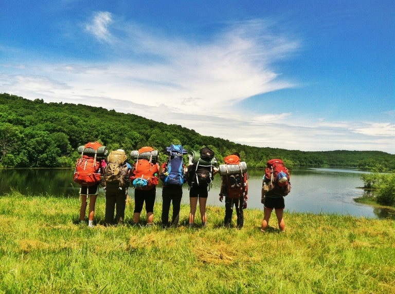 Students with back packs looking at a lake. 