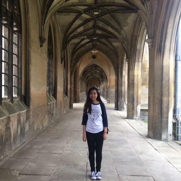 Rebecca Yeh stands in the courtyard of an old stone building in England.