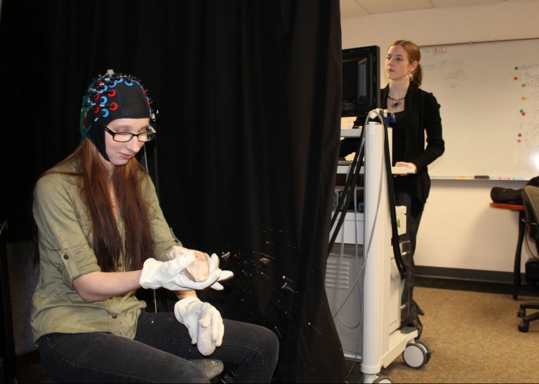 A volunteer creates an ancient Acheulean hand axe wearing a cap designed to measure brain activity.