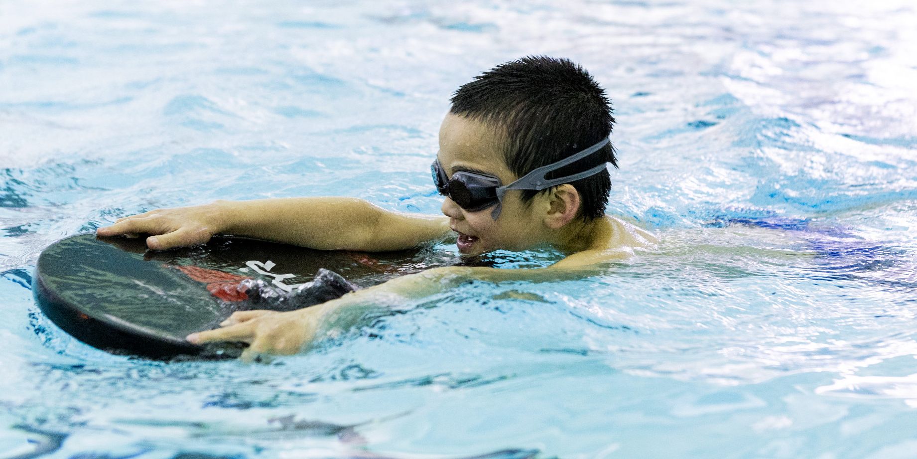 A swim student uses a kick board