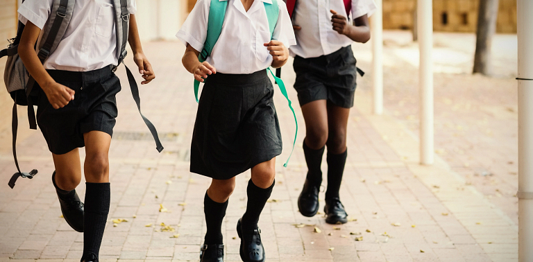 Students run toward the camera wearing school uniforms.
