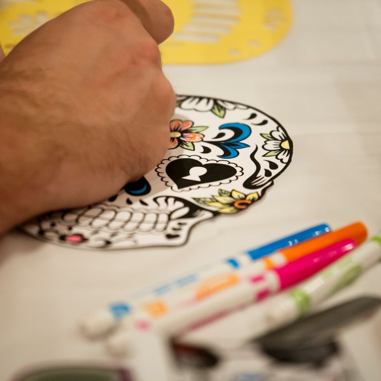 A drawing of a sugar skull being colored in with markers