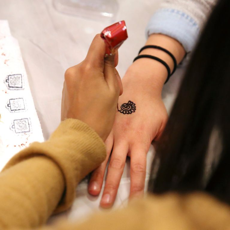 An attendee receiving a henna tattoo on their hand at the Pakistani Student Association booth