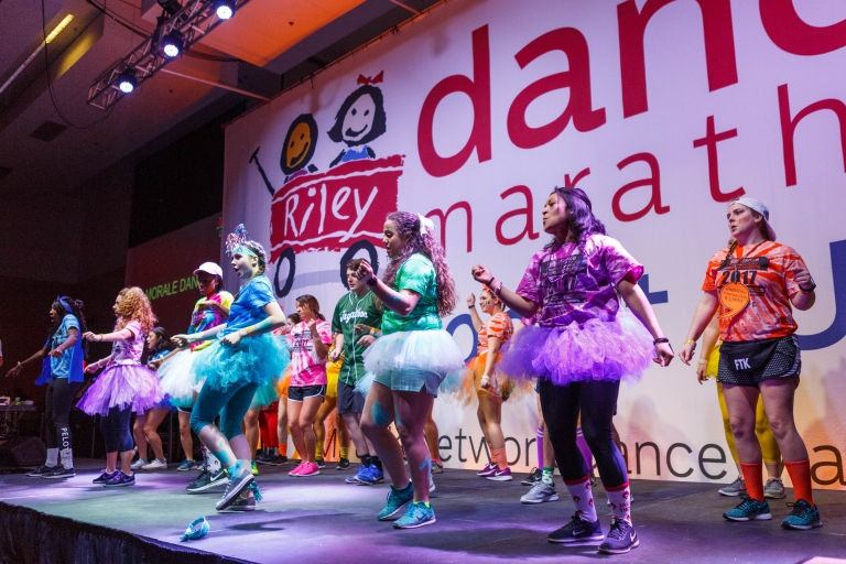 Students in colorful dress dance on stage during Jagathon's Dance Marathon.
