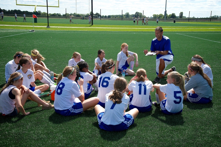 youth soccer players gather around their coach