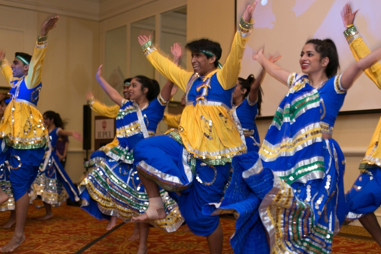 Men and women in brightly colored yellow and blue apparel dance