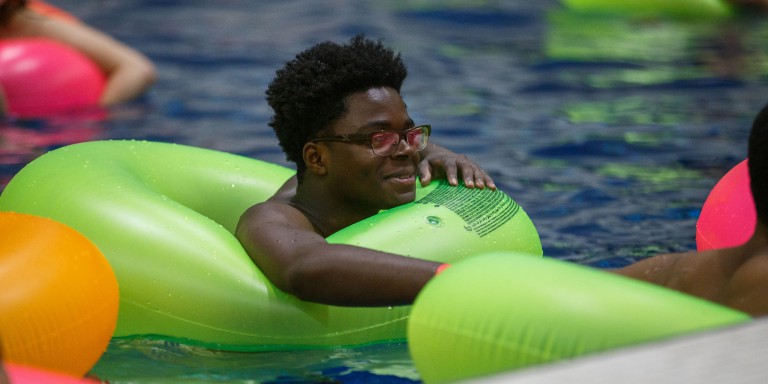 Student floats in a lime green pool inner tube at the IU Natatorium during Flick N Float.