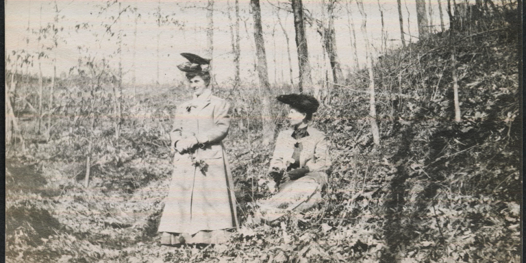A black and white photo of two women outdoors on a hill