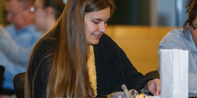 A young woman smiles while filling out her bingo card.