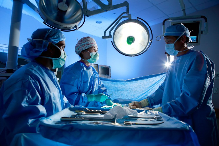 Three medical personnel conducting surgery