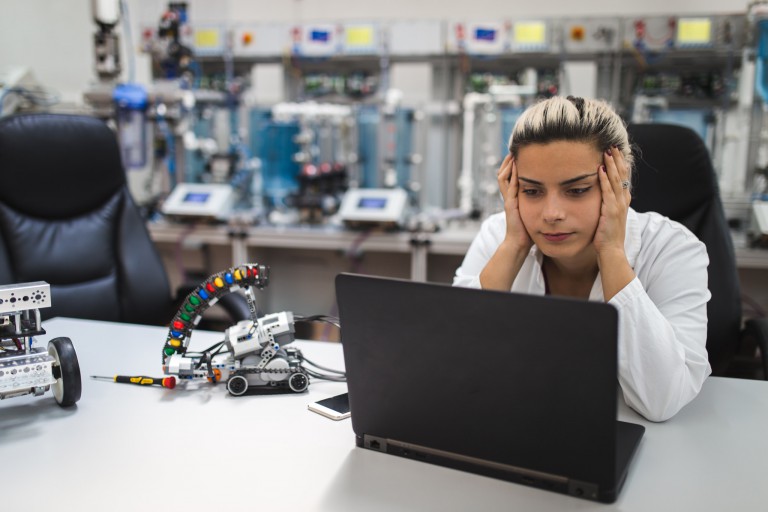A frustrated-looking scientist looking at a laptop in a laboratory