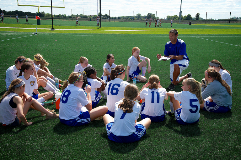 Youth soccer players gather around their coach