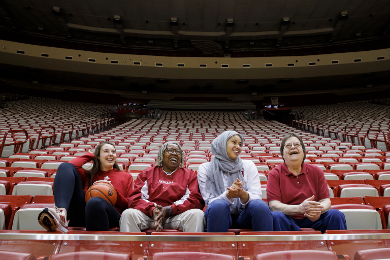 Four women's basketball players seated in Assembly Hall
