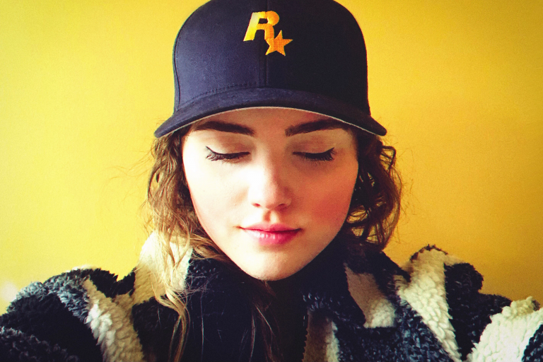 woman wears a blue hat with a yellow Rockstar Games logo